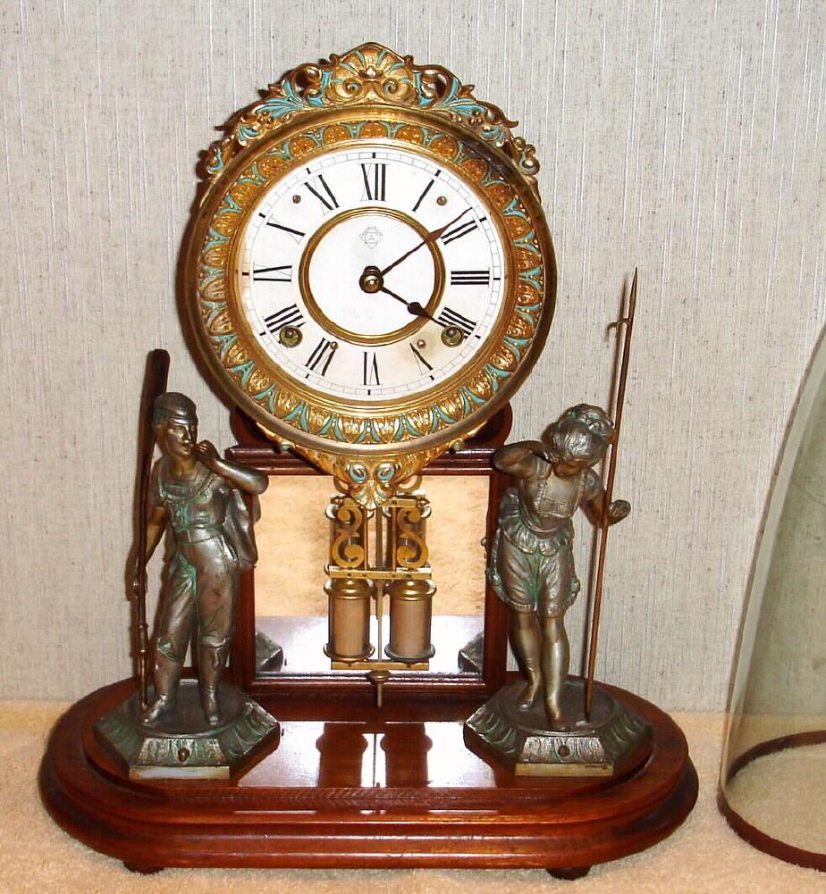 H. J. Davies, New York, "CRYSTAL PALACE" C.1877, with glass dome. 8-day bell strike movement, mounted to a walnut base, with a pair of statues, the barrel pendulum swinging in front of a framed mirror. — Antique Clocks Price Guide