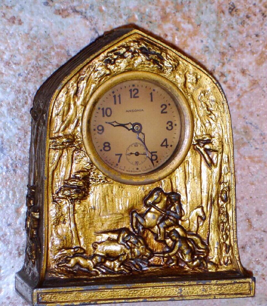 Ansonia Clock Co., cast pot metal BANK novelty, the case depicting dogs and horseback hunters capturing a wild boar, and the back with slots for coins and a key lock door to remove the money {this door soldered shut} — Antique Clocks Price Guide