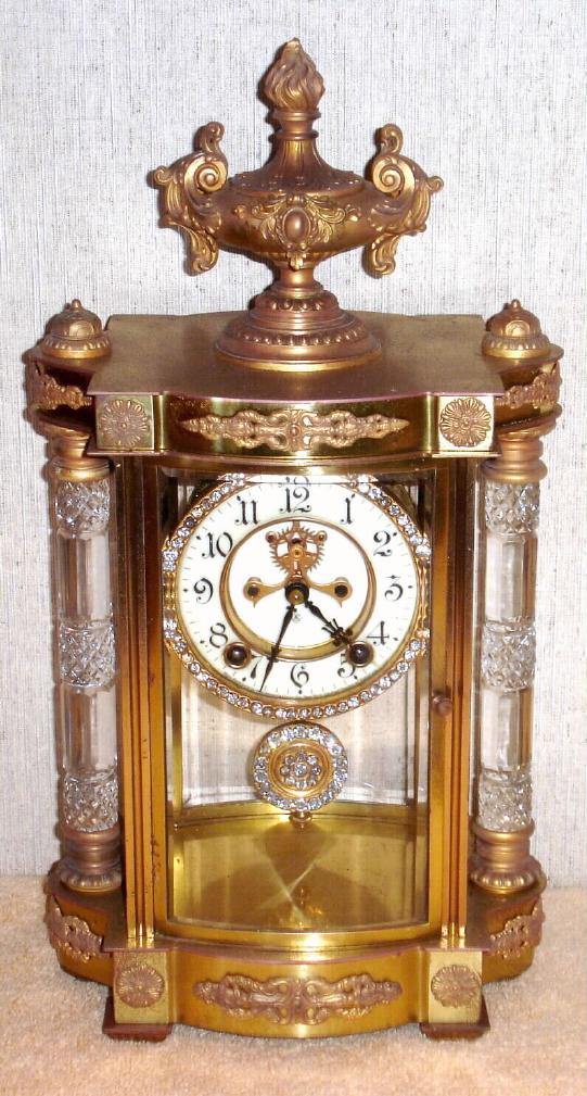 Ansonia Clock Co., New York, C.1904, "JUPITER", 4-glass, crystal regulator with open escapement on porcelain dial. This model with fancy brilliant surround bezel and pendulum/ — Antique Clocks Price Guide