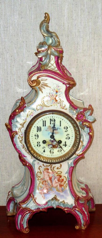 French, Japy Freres, ROYAL BONN, porcelain china, LE GRANDE, in attractive shades of magenta with gold highlights and 3 cherubic children on the front panel, shown playing, one with book, another with lyre. The porcelain dial also with fine decorations. — Antique Clocks Price Guide