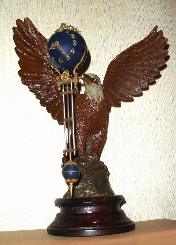 French, Mini Ball Swinger, suspended from a cast and patinated white metal eagle with brass beak, mounted to a turned wooden base. — Antique Clocks Price Guide