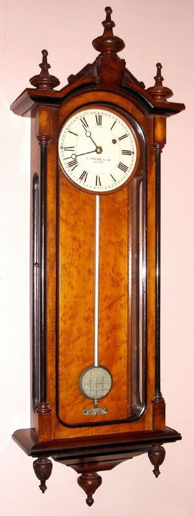 E. Howard and Co., Boston, REGULATOR No. 59, smallest size timepiece with 6" dial, weight driven, 8-day, C.1880, in a walnut case, glazed sides and with ebonized accents, three carved finials at bottom and 3 turned finials at top. — Antique Clocks Price Guide