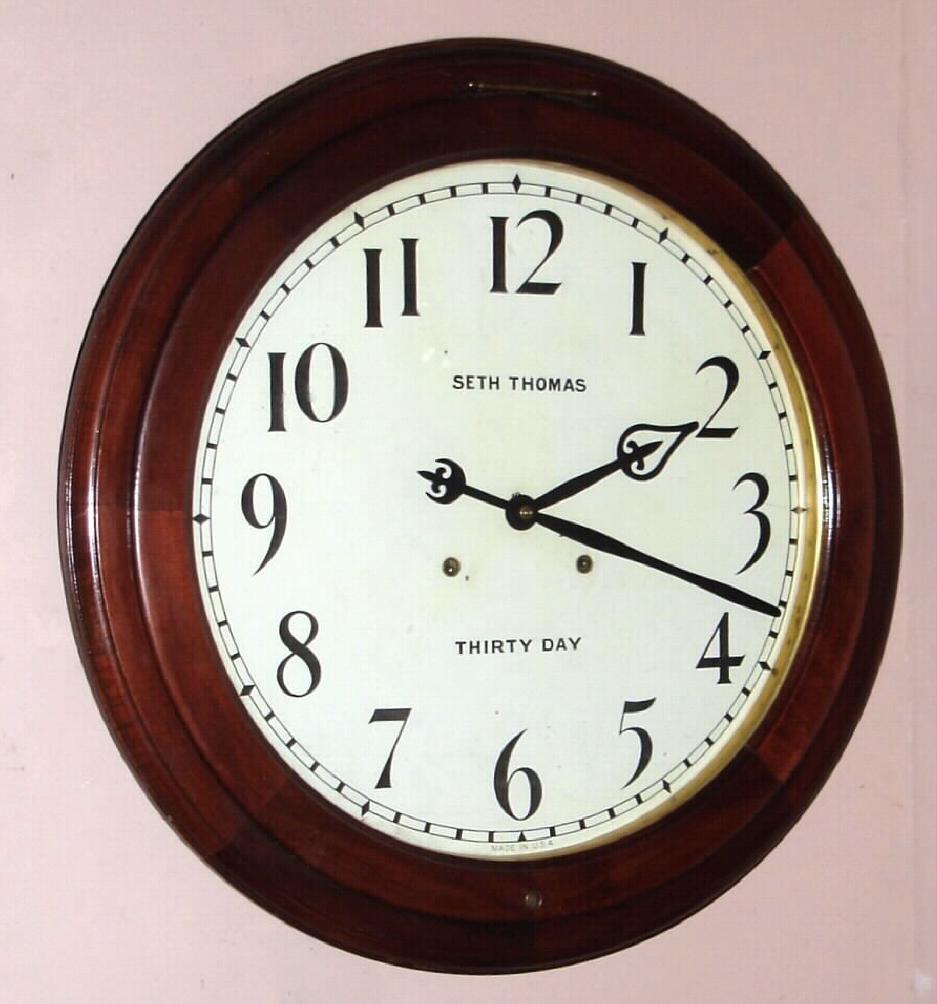 Seth Thomas Clock Co., Thomaston, Conn, "ARCADE" model, round gallery timepiece, with 30-day duplex spring movement, 18" dial, walnut case with bezel hinged above 12. — Antique Clocks Price Guide