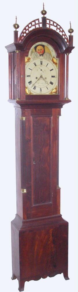 Benjamin Swan, Augusta {Maine}, C.1825, 8-day rolling moon tall clock, with painted, moon phase dial, housed in a mahogany and birch case, having a pierced fret trim atop the hood, and accented with 3 brass finials. Reeded quarter columns with brass capitals flank the waist door, and the plinth with scalloped apron and French feet. 2-weight. — Antique Clocks Price Guide