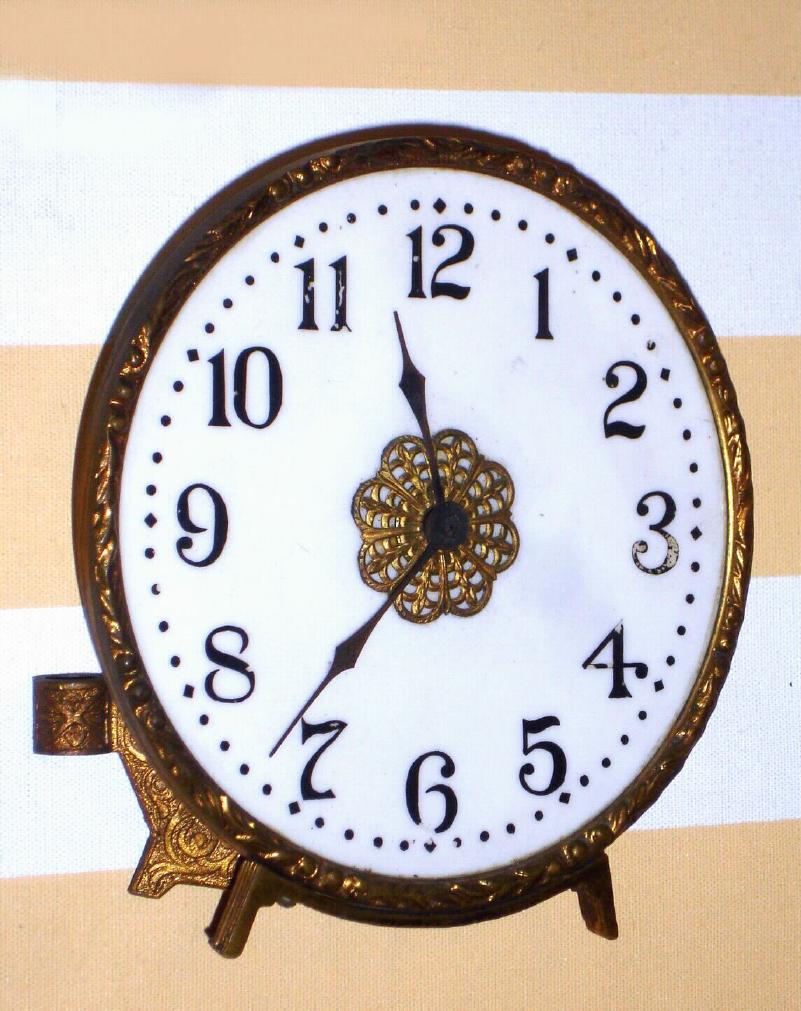 Waterbury Clock Co., C.1909, PEARL model "night clock", 30 hour back wind / set timepiece with an opalene [glass] dial, with gilt cast bezel and bracket to set on a gas burner (or to set as a strut on the mantel). With your gas lamp set on low, you had a nite lite and the visible time when you got up before day break. — Antique Clocks Price Guide