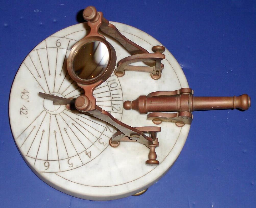 George Dorne, New York, No. 2, Circa 1973, Noon cannon. This is a copy based on a French style that was popular in the 18th century. The magnifying glass if set properly would concentrate the light to fire the loaded cannon at 12 o'clock. The setting angle of the magnifying glass can be set depending on the season to make it operate. The longitude and latitude are indicated on the marble base plate. — Antique Clocks Price Guide