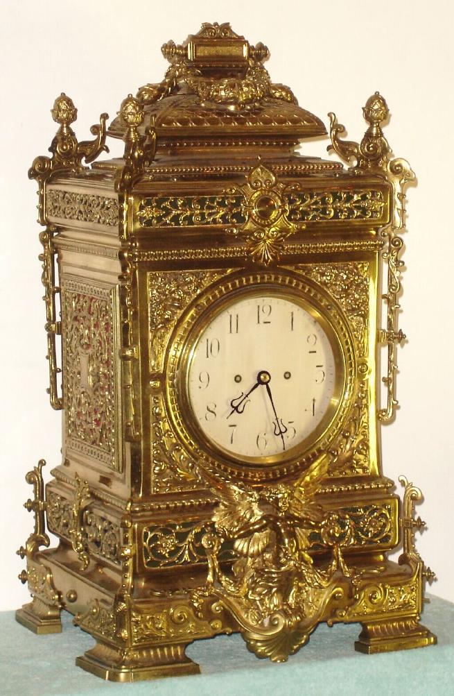 European, a very large Victorian cast brass table clock, with an equally large double chain fusee movement with heavy solid plates. Strikes the hours on a very large coiled wire cathedral gong. The case is profusely decorated with leaves and swags, a winged cherub below the 7" silvered dial with Arabic numerals, + surmounted by 4 pineapple finials and giant double acanthus swags with ribbon binding, c.1880. — Antique Clocks Price Guide