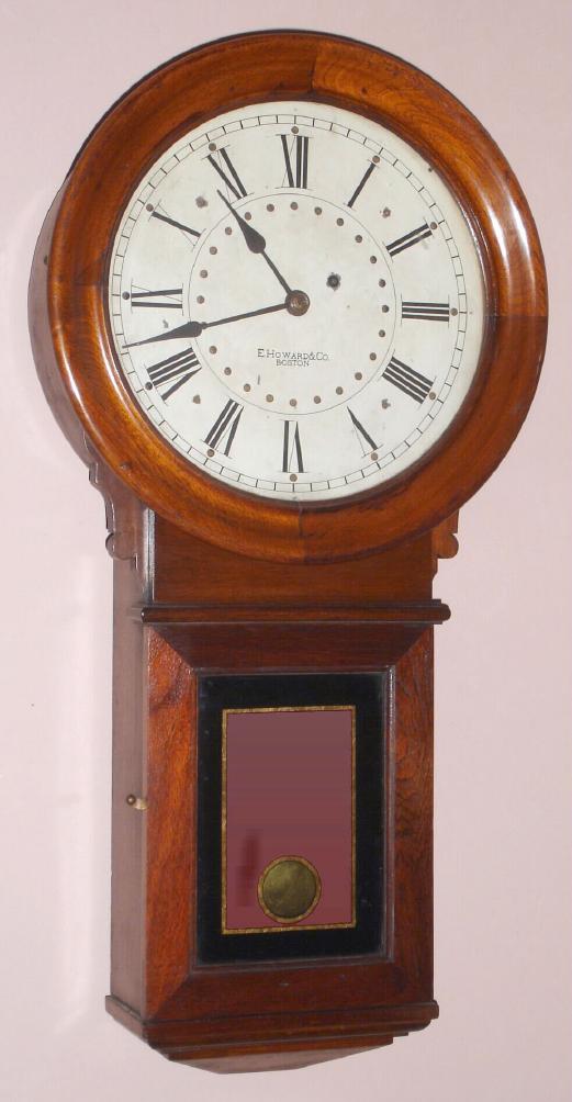 E. Howard and Co., Boston, "No. 70, PROGRAM CONTACT CLOCK", based on the No. 70 regulator and with and iron back behind the circular, laminated head, the dial insulated from the iron back on 4 wooden blocks, and with 2 bronze rings with holes at 5 minute intervals, the rings wired to an electrical stud in top of clock and the iron back/movement wired to the other stud. Walnut case. C.1910 — Antique Clocks Price Guide
