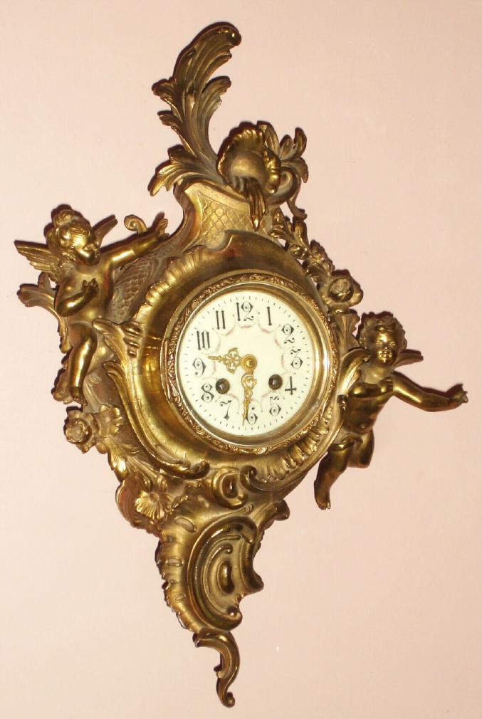 French, E. B. Serin, Paris, a brass cased hanging cartel clock in the Louis XVI style with a winged cherub either side of the dial, C.1870, mov't signed with Serin trademark "Qualite Soignee" logo. — Antique Clocks Price Guide