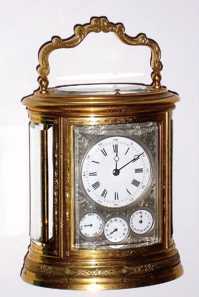 French, Oval and Engraved, brass cased carriage clock, Grande Sonneria [for the Spanish market], with day, date and alarm dials behind a silvered / engraved mask, and with a selector in the base for Grande Sonneria, Silencio, and Cuartos, the days of the week indicated in Spanish abbreviations. — Antique Clocks Price Guide