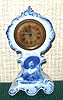 Ansonia Clock Co., small flow blue porcelain cased novelty with transfer of a gentleman with large hat, 1-day back wind, c.1910