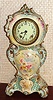 Ansonia Clock Co., Royal Bonn, "No. 506", slender porcelain clock in the French style, with flat porcelain dial, the white case with blue and aqua accents and gold highlights, and with a pink and magenta in the section below the dial, c.1900