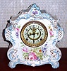 Ansonia Clock Co., C.1905, Royal Bonn, "LA VOGUE" porcelain china cased clock, with 8-day, gong strike mov't with open escapement on porcelain dial, in a creamy case with light blue accents and gold highlights, and with multi colored floral trim on the case front and sides.