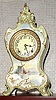 Ansonia Clock Co., C.1895, Royal Bonn, "LA BOURGOGNE" porcelain china cased clock, with 8-day, gong strike mov't with one piece creamy dial with red trim between the numerals, and the lower scene of a Dutch harbor with sailing ship.