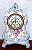Ansonia Clock Co., C.1905, Royal Bonn, "LA CALLE" porcelain china cased clock, with 8-day, gong strike mov't with open escapement on porcelain dial, in a white china case with light blue accents and gold highlights, the case decorated with yellow and magenta flowers.