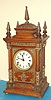 Ansonia Clock Co., C.1894, "CABINET ANTIQUE", oak cased mantel clock with brass trimmings, this one with one piece porcelain dial. Note variations in movement between this one and lot with fancy dial. This one has low mount iron based gong, as used in many mantle models.