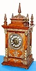 Ansonia Clock Co., C.1894, "CABINET ANTIQUE", oak cased mantel clock with brass trimmings, this one with one with fancy dial, w/ individual porcelain cartouche numerals.. Note variations in movement between this one and lot with plain dial. This one has fancy embossed plates and cups protecting the springs, plus tall gong standard.