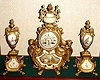 French, S. Marti, 3-piece garniture, gold painted white metal, with hand painted plaques and side urns, 8-day, strike, with fancy painted dial with floral wreath and gilt brass hands.