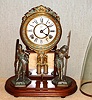 H. J. Davies, New York, "CRYSTAL PALACE" C.1877, with glass dome. 8-day bell strike movement, mounted to a walnut base, with a pair of statues, the barrel pendulum swinging in front of a framed mirror.