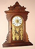 E.N. Welch, Forestville, Conn. gingerbread clock 8 day time and strike spring driven mvt in walnut case with Roman numeral paper over gilt dial, c1890