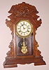Waterbury Clock Co., Waterbury Conn. "KELSO" gingerbread clock with 8 day time and strike on gong spring driven mvt in oak case with Rococo style 6" paper over gilt pan dial, c1891