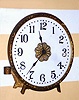 Waterbury Clock Co., C.1909, PEARL model "night clock", 30 hour back wind / set timepiece with an opalene [glass] dial, with gilt cast bezel and bracket to set on a gas burner (or to set as a strut on the mantel). With your gas lamp set on low, you had a nite lite and the visible time when you got up before day break.