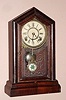 New Haven Clock Co., "GEM EXTRA", 8-day time and gong strike mantel clock in a Gothic case with rosewood veneer, and with pressed glass pattern pendulum.