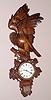 Swiss carved wall clock from the Interlaken region of Switzerland well known for producing these quality carved clocks, unknown hardwood with finely carved eagle peering out with life-like glass eyes perched on roost containing French 8 day time only clock movement with platform lever escapement and Roman numeral porcelain dial, c1900