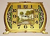German desk clock with 8 day spring driven Swiss movement in Art Deco gilt case with center inset painted ivory panel on dial with pastoral scene and geometric enameled decoration bordering Arabic numerals, c1925