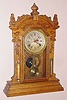 Waterbury Clock Co., pressed oak gingerbread clock with central calendar, time and gong strike, 8-day. Also with thermometer and weather tube intact, c.1900.