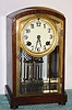 Waterbury Clock Co., C.1914, "TROUVILLE", mahogany cased 'crystal regulator', with 2-vial pendulum and porcelaian dial.