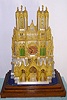 French, Raingo Frs, Paris, bronze, silvered brass and ormolu clock in the form of Reims Cathedral, c.1850. Cathedral of Our Lady in the City of Reims, stands in the Champagne-Ardennes region of France, and is considered one of the finest examples of the High Gothic style of architecture. The kings of France were once crowned in Reims Cathedral. Note that dozens of little cast and chased 'Saints' line the windows, exactly as the real building. Clock sets on its original rosewood base, and with a glass cover/ 5 panes in a wooden frame. Well made silk thread movement is signed as above.