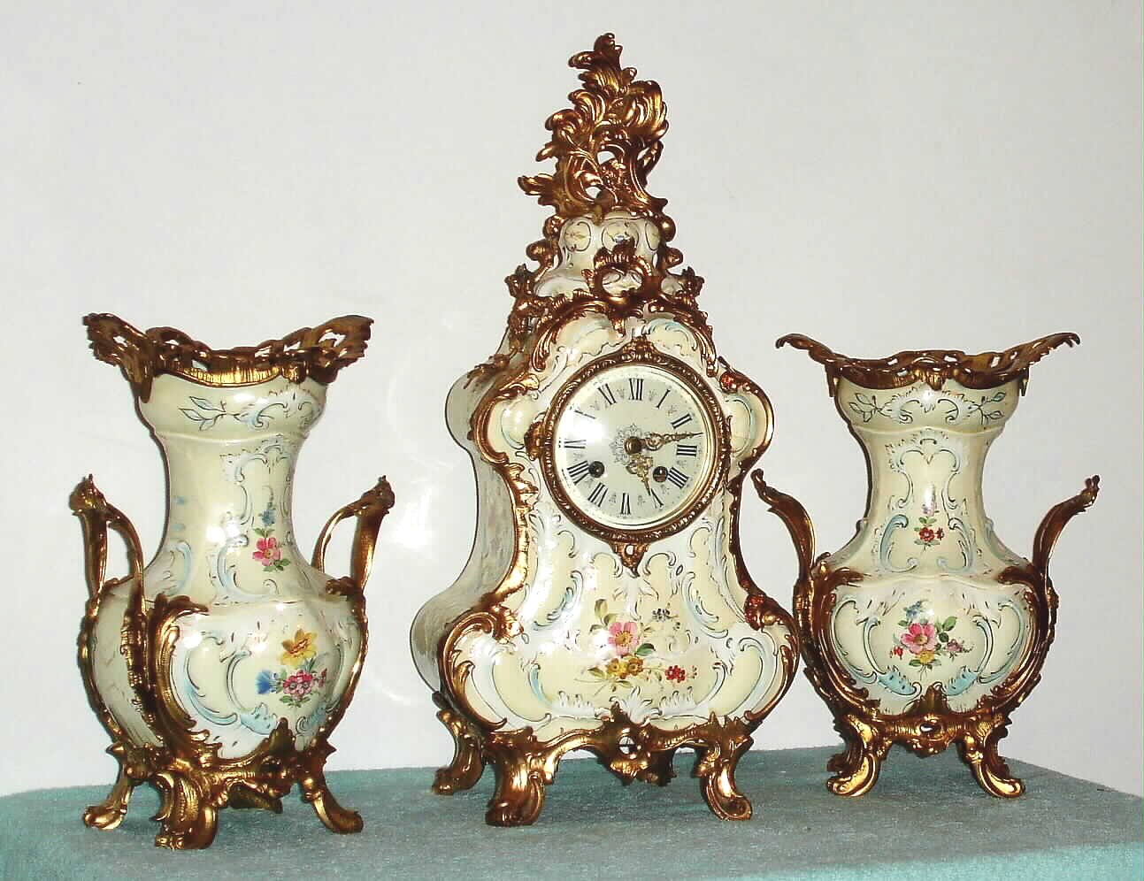 German, Lenzkirch, 3-piece mantel set of porcelain with ormolu adornments, and with quality round movement with porcelain dial and fancy brass hands, the case and side pieces with floral trim, c.1875. — Antique Clocks Price Guide