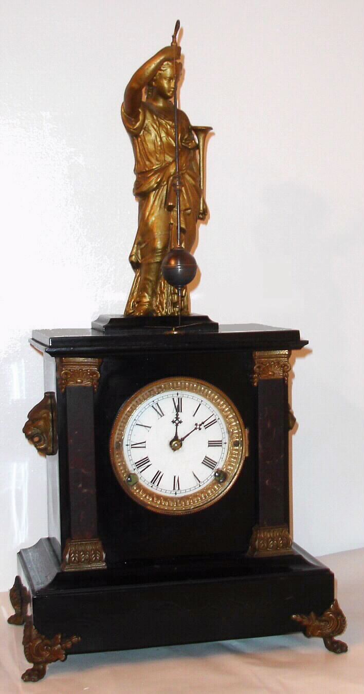 F. Kroeber Clock Co., New York, "Noiseless Rotary No. 4" mantel clock with 8 day time and strike spring driven movement in enameled cast iron case with marbleized columns and painted metal figure supporting rotary pendulum with bronzed ornaments, c1882. Note the statue holds a ball style pendulum that travels in a conical pattern, as it is driven by a rotating stud projecting upward from the movement. Kroeber and Briggs were the only two Americans known to utilize this French invention, and Terwilliger's versions were made in Germany. — Antique Clocks Price Guide