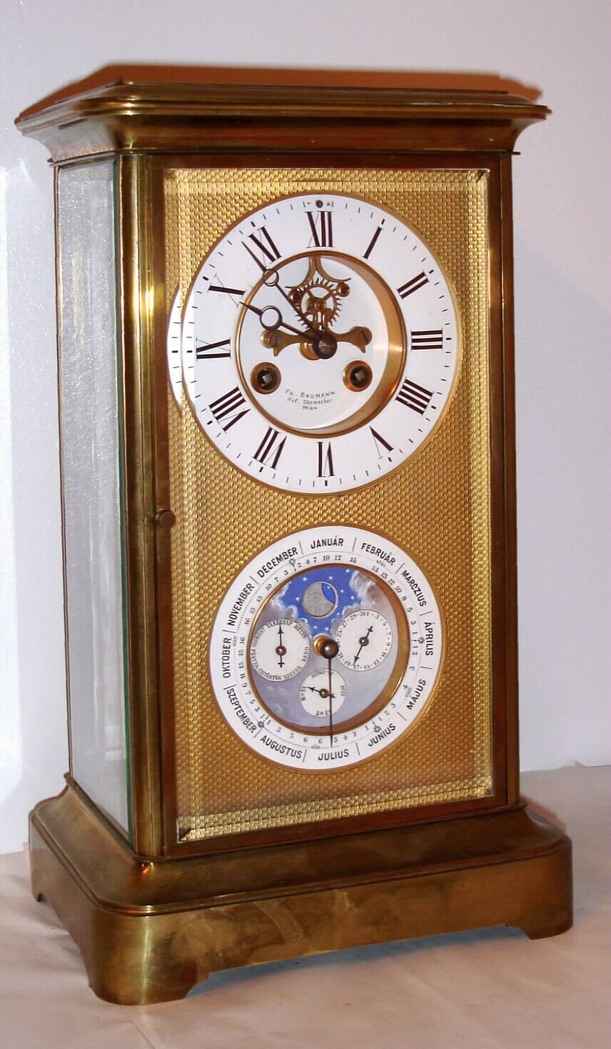French, 8-day time/strike brass and glass double dial crystal regulator calendar clock retailed by Fr. Baumann, Wien., the calendar dial is perpetual, correcting for short months, and with phases of the moon. Dials are offset by a stippled and gilt brass mask, C.1900 — Antique Clocks Price Guide