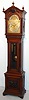 Tiffany and Co., New York, tall case clock, 8 day, quarter chiming, three weight driven movement and playing choice of Westminster chimes on four gongs or Whittington chimes on a nest of 8 bells, in mahogany case with barley twist columns flanking hood and beveled glass door and carvings of the North Wind at the top of the hood and on the front of the base and a brass dial with two discs for silent / strike and Whittington / Westminster and moon phase, c1915