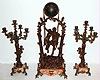 French, very large swing clock, 3 piece set with matching 5 light candle stands. A romantic couple are seated in a swing, appearing to suspend by rope from entwined branches joined at the top, and with a brass title plaque: "Idylle Printaniere, par Geo Maxim", the couple swinging from side to side without apparent impulse, C.1890