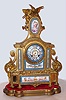 French mantel clock with 8 day time and strike on bell movement in gilt spelter case, set with Sevres type porcelain painted panels and dial on wooden conforming base, c1880.