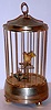 Music box playing "Jingle Bells" with bird in brass cage and mechanical movement, the bird pivots from perch to perch as tune plays, c1960