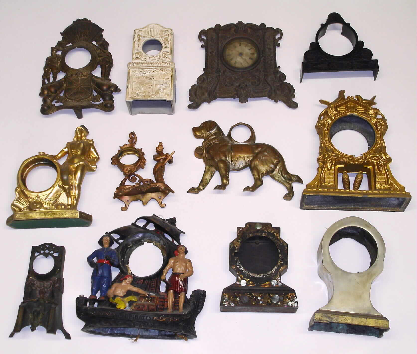 Twelve cast-metal clock cases. Includes multi-color pirates, standing dog, seated woman, standing soldiers, MOP iron-front, cuckoos, woman harpist novelty, etc. — Antique Clocks Price Guide