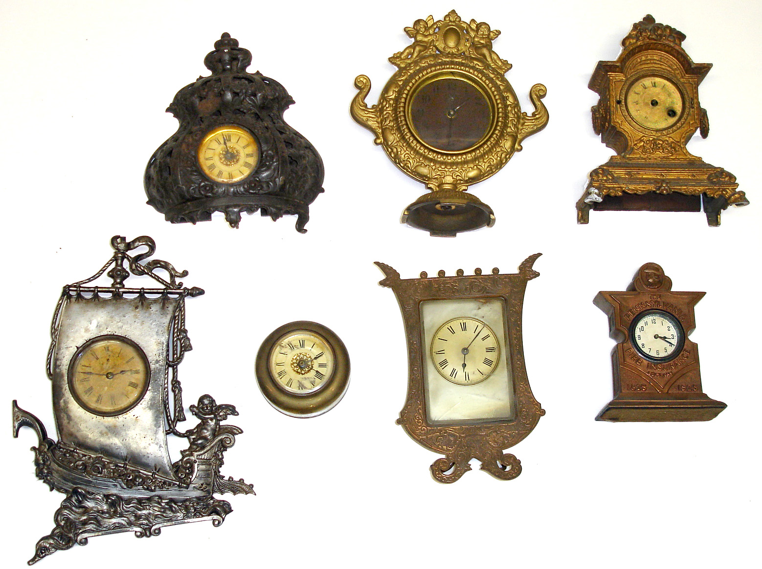 Seven cast-metal novelty clocks. Includes Meridan silver-plate sailing ship, Pennsylvania Fire Insurance Co. 1825-1925, French silver-dial strut, etc. — Antique Clocks Price Guide
