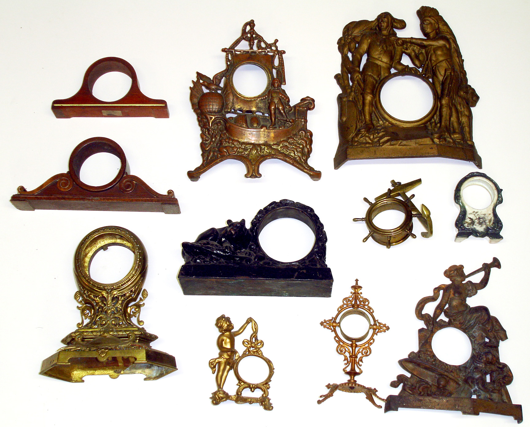 Eleven small clock cases. Includes two wood tambours, one mini China, and cast-metal cases of crouching lion, sailing ship, anchor, standing nymph, Native Americans, etc. — Antique Clocks Price Guide