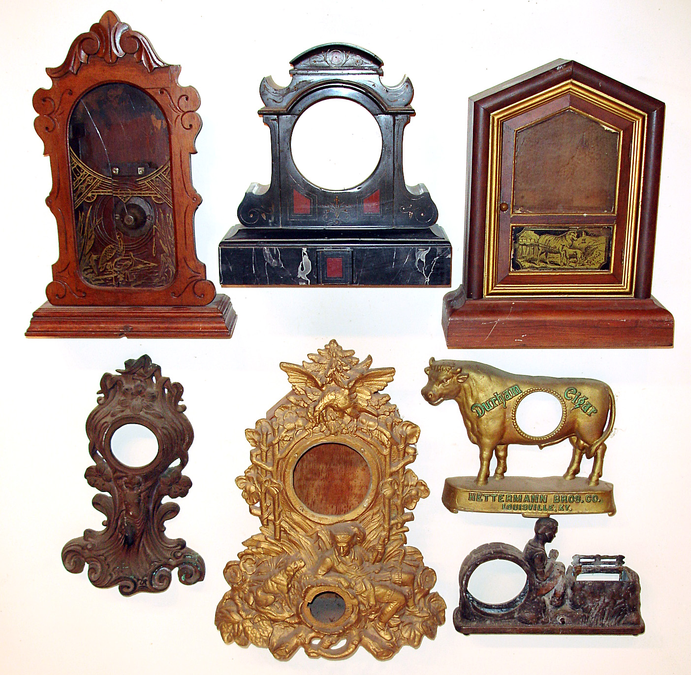 Seven clock cases- one French black marble, two mahogany including a cottage and parlor. There are also four cast metal including one gold iron front and an advertising "Durham Cigar". Tallest is 20". — Antique Clocks Price Guide