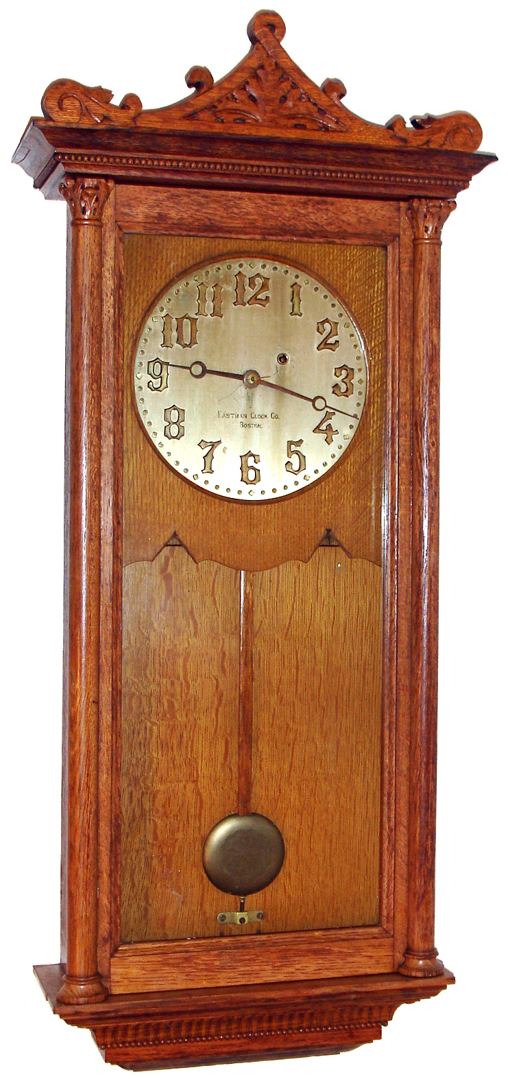 Eastman Clock Co., Boston "Regulator" wall clock 8 day time only weight driven movement in oak case with carved top and Corinthian style columns, matching beading above door and around base and solid brass dial with raised brass numerals, c1890 — Antique Clocks Price Guide
