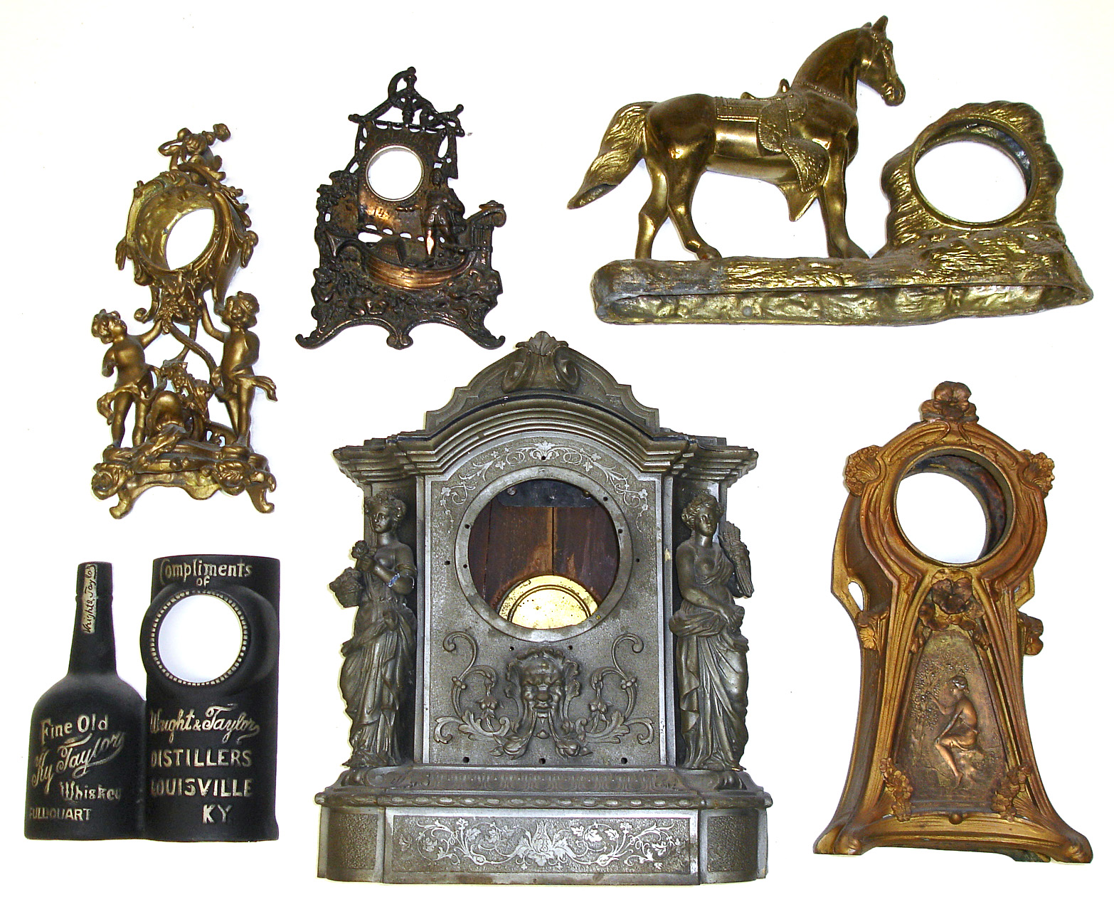 Six cast-metal clock cases. Includes great novelty case with standing figures and dolphin, a 1492 Columbus, an advertising for Kentucky whiskey and an oversize case with two standing female figurals. — Antique Clocks Price Guide