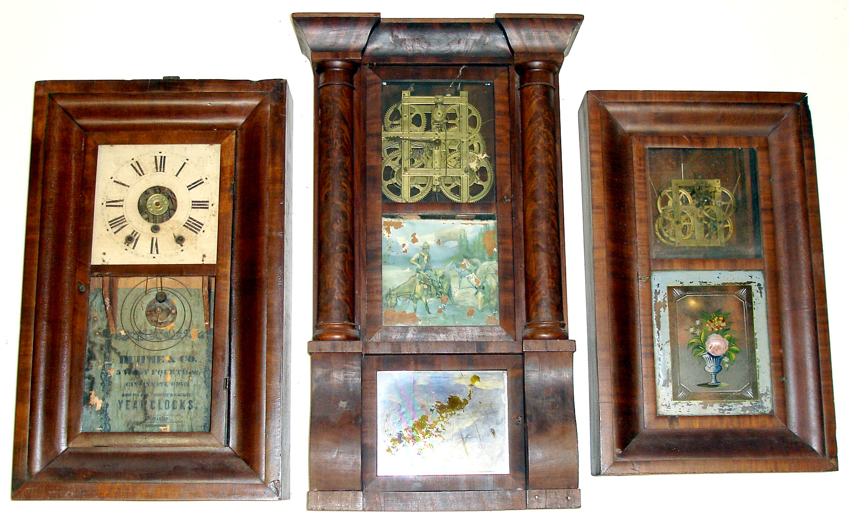 Three Connecticut weight driven shelf clocks, incomplete. Smallest is 30 hour Sperry and Shaw OG with pretty floral tablet but bare zinc dial plate. Middle is Duhme and Co., Cincinnati 8 day OG with built-in alarm, no glasses. Largest is Waterbury column and cornice with big 8-day strap movement, no dial or label, 33" high. — Antique Clocks Price Guide