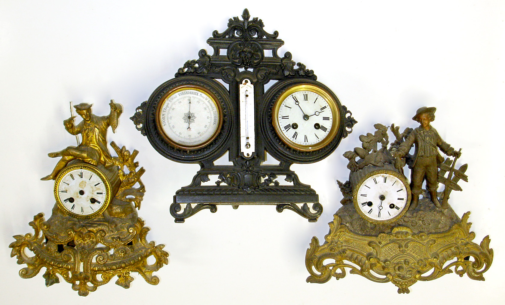 Three French cast metal 8 day mantel clocks. Two are ornate gilt figurals with reeded drum movement holders. Third is strut style weather station with twin scale thermometer, aneroid barometer with "Vebanderlyk" etc. readings, and bell strike movement with tic-tac pendulum, 14" tall. — Antique Clocks Price Guide
