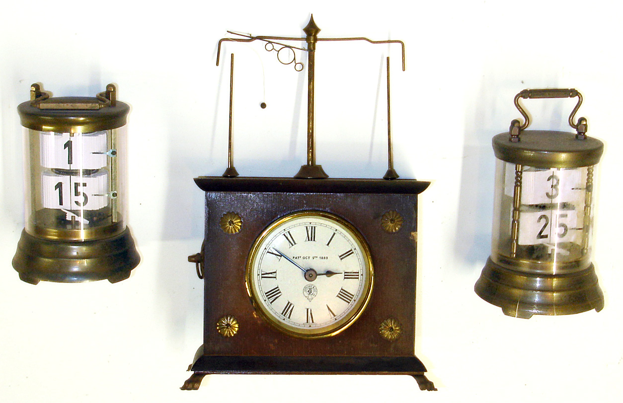 Three Horolovar reproduction German 30 hour novelty clocks. Two are modern versions of Plato flip card timepieces with 7 jewel bottom wind movements, 6" tall. Flying ball pendulum clock, with Jerome and Co. 1883 dial, is 10" tall. — Antique Clocks Price Guide
