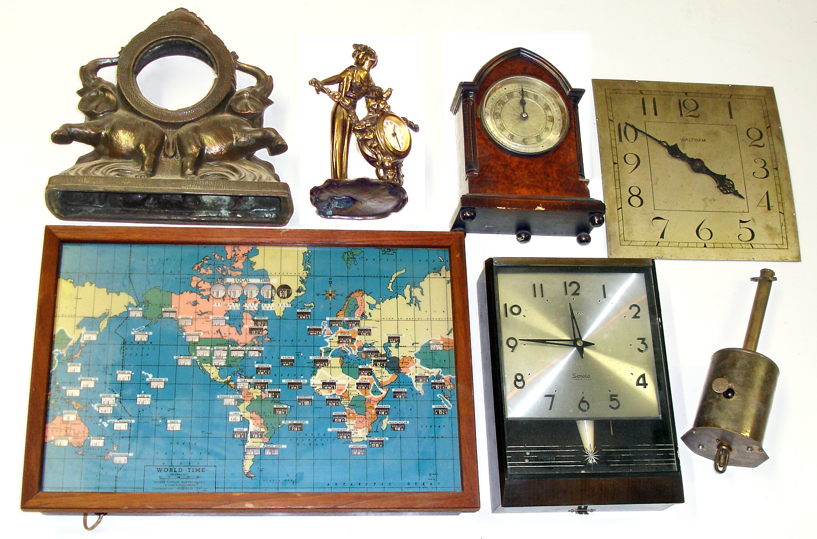 Seven pieces, mixed lot. Oldest is 19th-century Salter's English bottle jack for turning meat before the open hearth. Newest is "World Time" electric global map and local times. Also includes Seiko "Sonola" transistor plastic wall clock, figural brass novelty clock with modern German fit-up, rearing elephants case, French "Hatot" battery-powered small cabinet clock, and Waltham 11" square dial with hands and 37-size movement. — Antique Clocks Price Guide