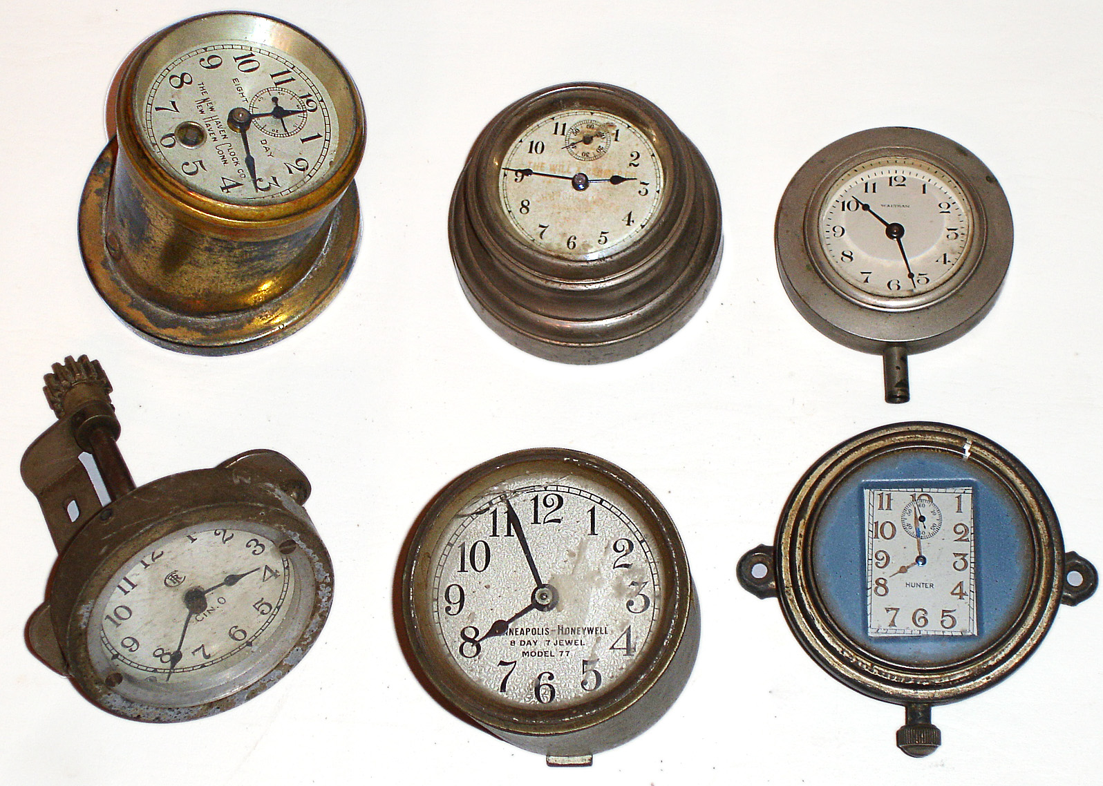 Six small mounted metal clocks: five auto clocks and one Minneapolis Honeywell 8 day 7 jewel Model 77 for early thermostat. Car clocks include an 8 day New Haven in angled case, Seth Thomas with dial faintly lettered for "The Will and Baumer Co. Church Candles, Syracuse N.Y.", a Hunter with a rectangular dial, a Waltham with a small white dial, and a "CTR" logo and "Cin.O." on its dial. — Antique Clocks Price Guide